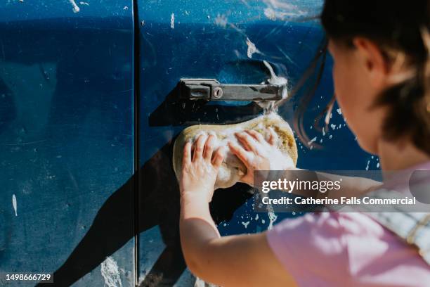 a child washes bird droppings and mud from the side of a car - hubcap stock pictures, royalty-free photos & images