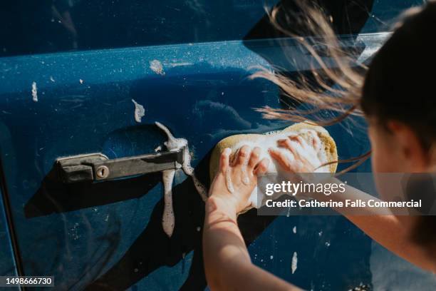 a child washes bird droppings and mud from the side of a car - hubcap stock pictures, royalty-free photos & images