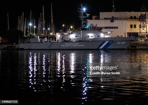 Members of the Greek Coast Guard move 79 recovered bodies to a makeshift morgue as migrants sleep in a hangar where more than 100 have been...