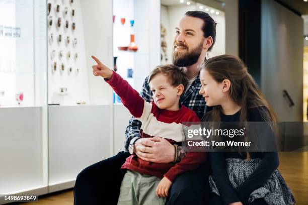 father hugging children while visiting museum - facial hair stock pictures, royalty-free photos & images