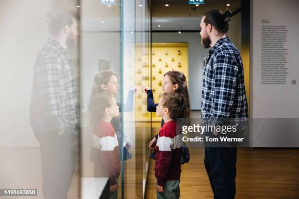 father looking at museum exhibit with two kids - history museum stock pictures, royalty-free photos & images