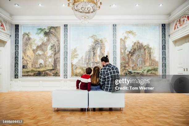 father enjoying paintings on display while visiting museum with children - girl museum stockfoto's en -beelden