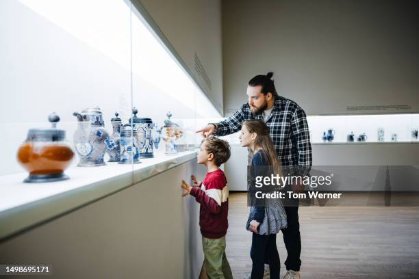 father pointing at exhibit while visiting museum with children - 歴史博物館 ストックフォトと画像