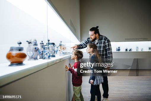 Father Pointing At Exhibit While Visiting Museum With Children