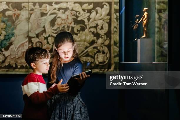 brother and sister looking at ipad while exploring museum together - boy skirt stock pictures, royalty-free photos & images