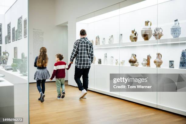 father and two children walking through museum exhibits - musée historique photos et images de collection