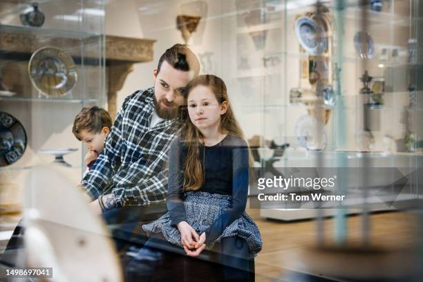 single father sitting with daughter and looking at museum exhibits - museum visit stock pictures, royalty-free photos & images