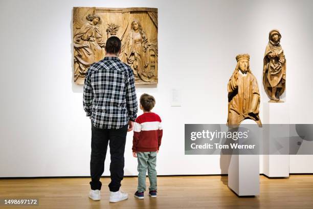 father and young son looking at historical display in museum together - history museum stock pictures, royalty-free photos & images