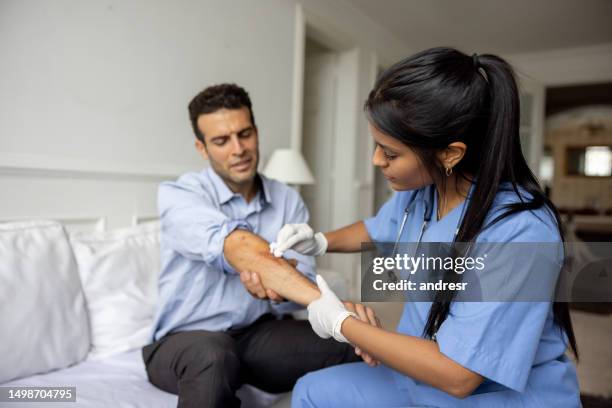 doctor on a house call cleaning a man's wound - desinfetar imagens e fotografias de stock