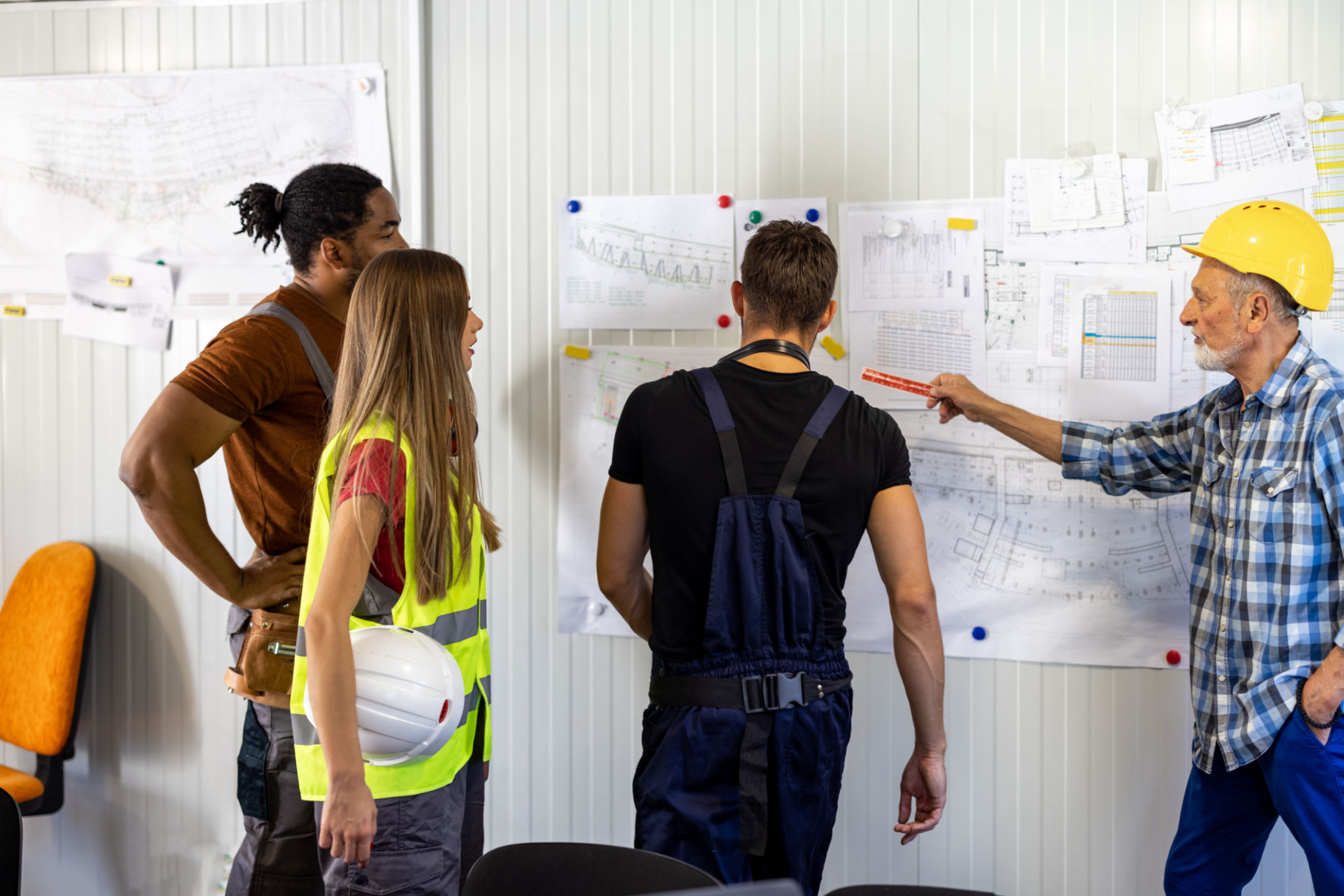 A Senior Construction Worker is Analyzing Project Plans with Young Coworkers. A Senior Construction Worker is Analyzing Project Plans with Young Coworkers.