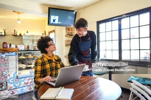 waiter serving coffee to working woman at a coffee shop - modern cafe stock pictures, royalty-free photos & images