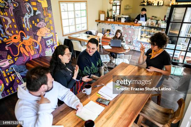 colleagues doing a language sign class at a coffee shop - sign stock pictures, royalty-free photos & images