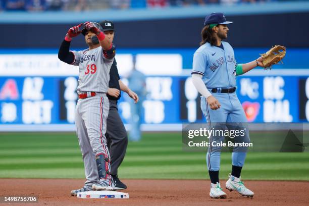 Donovan Solano of the Minnesota Twins celebrates on base in front of Bo Bichette of the Toronto Blue Jays as he hits a double in the the first inning...