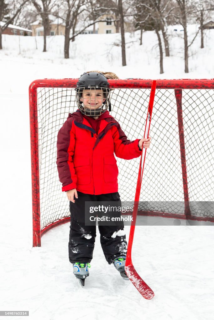 Garçon avec un bâton de hockey souriant à la caméra