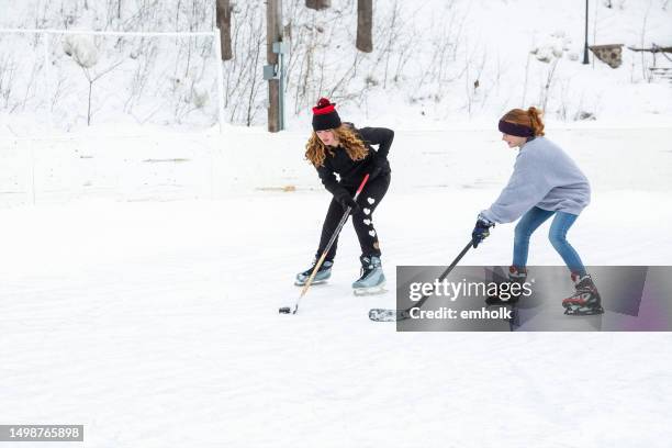 two girls playing ice hockey in winter - ice hockey day 10 stockfoto's en -beelden