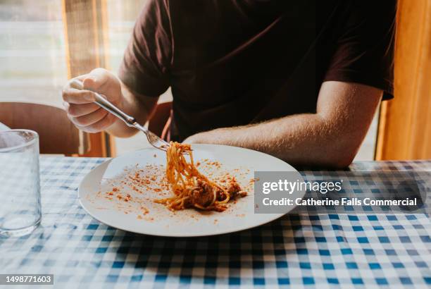 a man eats a plate of spaghetti bolognese with meatballs at a  dining table - plate of food stock pictures, royalty-free photos & images