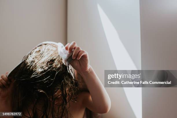 a independent young child gets herself ready, drying her wet hair. - hair conditioner stockfoto's en -beelden