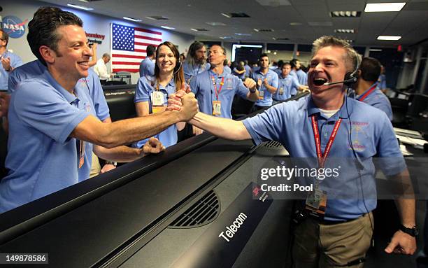 Flight director Keith Comeaux, right, celebrates with Martin Greco after a successful landing inside the Spaceflight Operations Facility for NASA's...