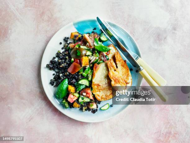 plate of pan fried chicken breast with fresh salad and black lentils on pink background - chicken meat stock pictures, royalty-free photos & images