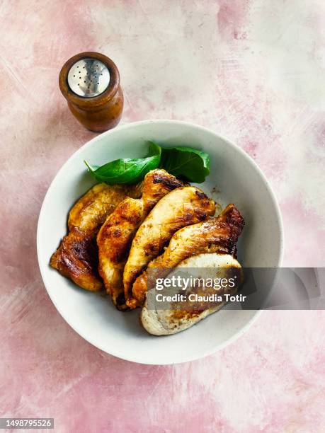plate of pan fried chicken breast on pink background - gegrillte hühnerbrust stock-fotos und bilder