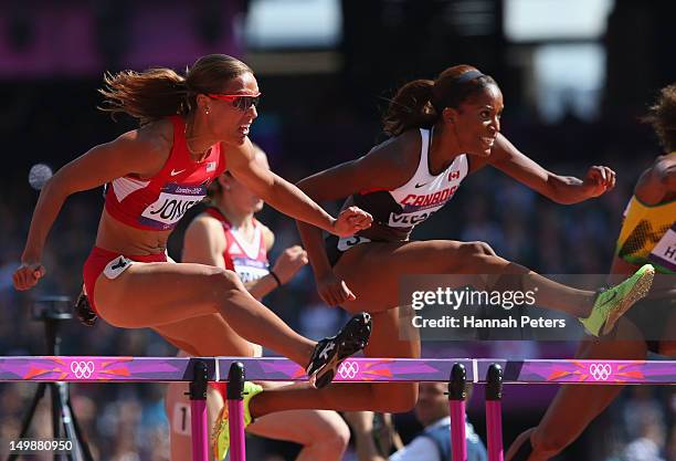 Lolo Jones of the United States jumps over a hurdle alongside Phylicia George of Canada in the Women's 100m Hurdles heat on Day 10 of the London 2012...