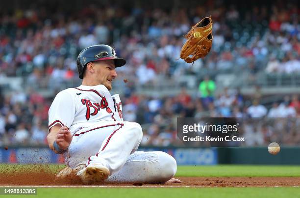 Sean Murphy of the Atlanta Braves slides safely into third base after colliding with Ryan McMahon of the Colorado Rockies and knocking his glove off...