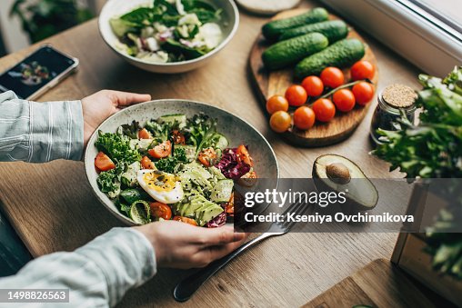 Woman mixing delicious superfood salad ingredients with wooden spoons in kitchen Woman mixing delicious superfood salad ingredients with wooden spoons in kitchen
