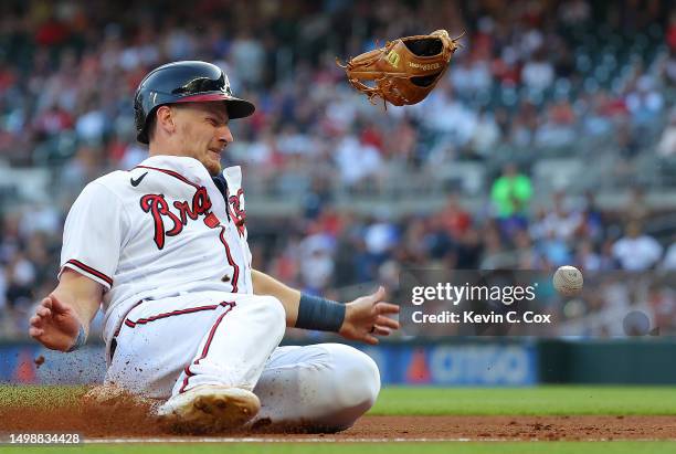 Sean Murphy of the Atlanta Braves slides safely into third base after colliding with Ryan McMahon of the Colorado Rockies and knocking his glove off...