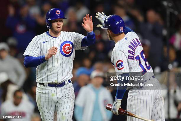 Ian Happ of the Chicago Cubs high fives Tucker Barnhart after scoring on a RBI sacrifice fly by Christopher Morel during the sixth inning against the...