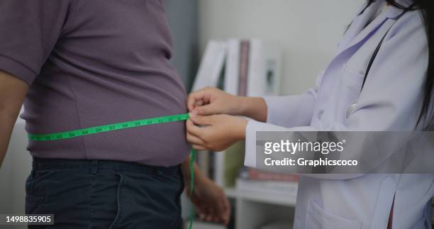 nutricionista que mide la cintura de un hombre con sobrepeso en una clínica de pérdida de peso - fat fotografías e imágenes de stock
