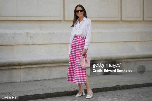 Alba Garavito Torre wears black sunglasses from Ray Ban, white pearl and gold chain pendant earrings, a transparent large pearls long necklace, a...
