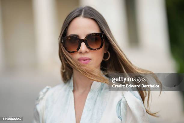 Maria Rosaria Rizzo wears brown marble print pattern sunglasses from Isabel Marant, a white and pale blue marble print pattern silk buttoned long...