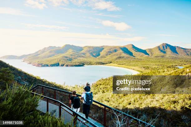 vale la pena camminare: giovane famiglia che cammina nel bush in tasmania, in australia, ammirando la vista al freycinet np. - explore australia foto e immagini stock