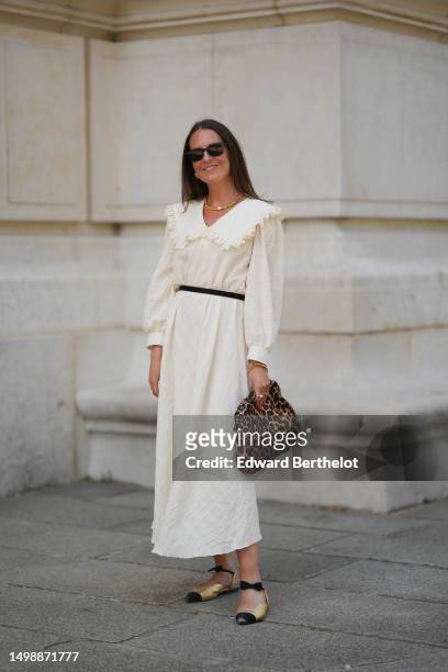 Alba Garavito Torre wears black sunglasses from Ray Ban, gold earrings, a gold pearls and one white large pearl necklace, a white latte ruffled linen...