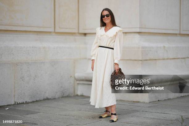 Alba Garavito Torre wears black sunglasses from Ray Ban, gold earrings, a gold pearls and one white large pearl necklace, a white latte ruffled linen...