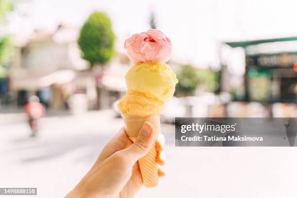 ice cream consisting of three balls in a waffle cone in a hand close-up. - ice cream cone stockfoto's en -beelden
