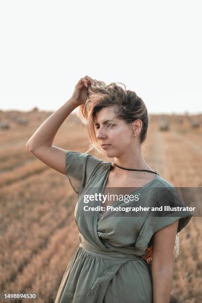 junge frau, stehen, auf, abgeerntet, feld, mit, strohballen. landwirtschaftlicher hintergrund mit kopierraum. sommer- und herbsterntekonzept. - stoppelfeld stock-fotos und bilder