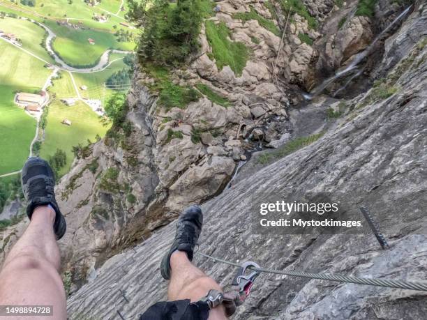 pov of man on via ferrata climbing up a ladder on a rock face - male feet on face stock pictures, royalty-free photos & images