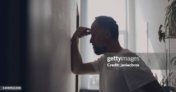 depressed man in the hall. rubbing the forehead - head in hands silhouette stock pictures, royalty-free photos & images