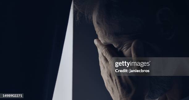 anxious man looking out the window with worry. hiding face in hands - head in hands silhouette stock pictures, royalty-free photos & images