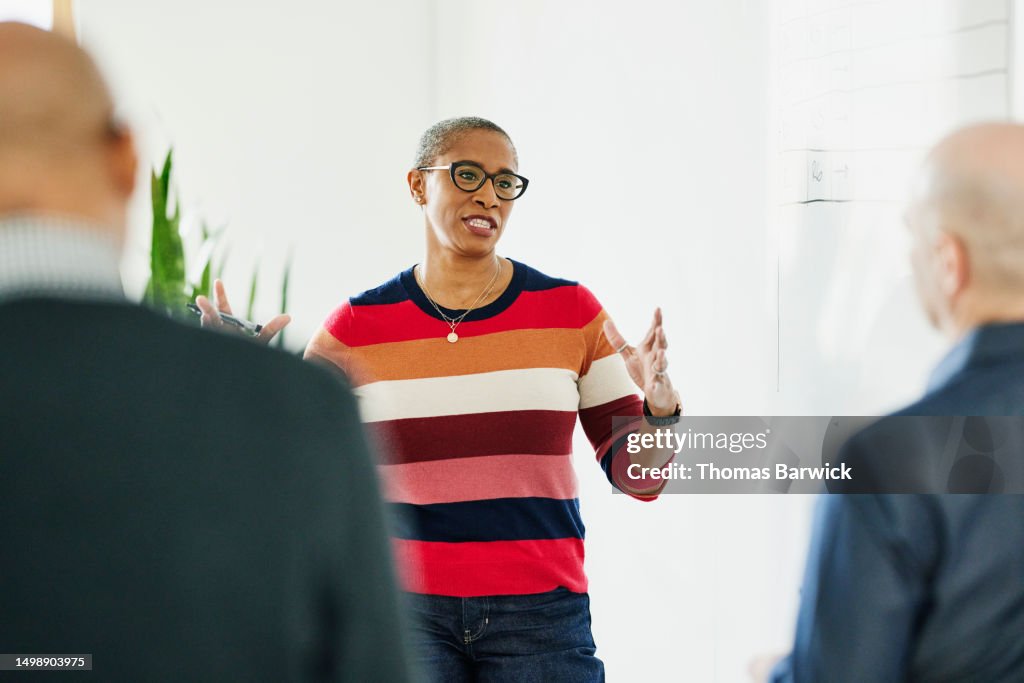 Medium shot businesswoman leading meeting with coworkers in office