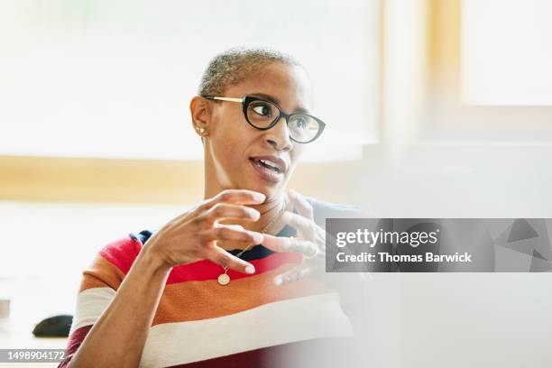 medium shot businesswoman in discussion with colleague at workstation - one person talking stock pictures, royalty-free photos & images