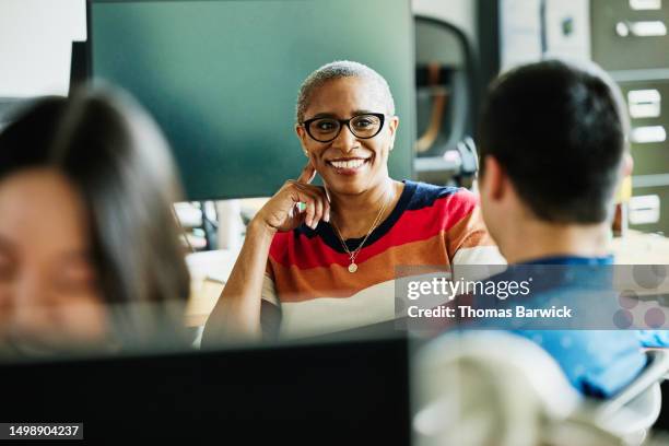 medium shot businesswoman in discussion with colleagues in office - trabajo-de-oficina fotografías e imágenes de stock