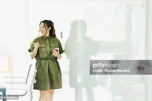 medium wide shot of businesswoman leading team meeting conference room - grünes kleid stock-fotos und bilder