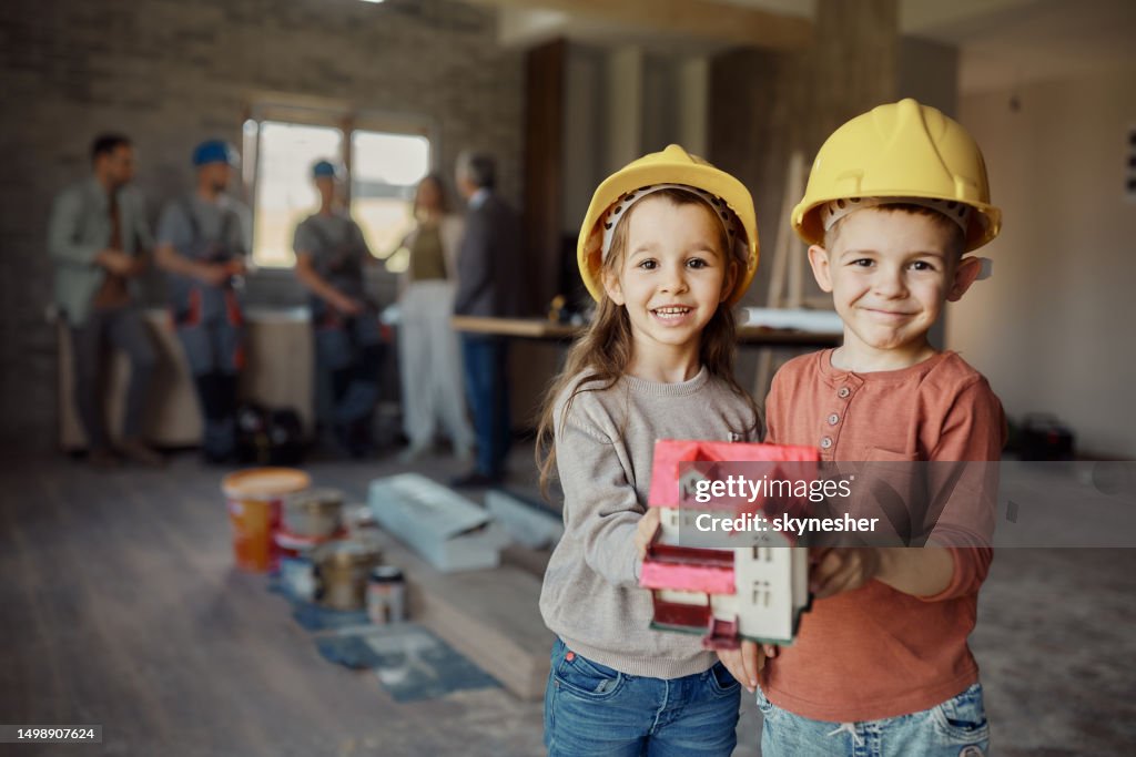 Glückliche kleine Architekten mit Musterhaus beim Renovieren des Hauses.
