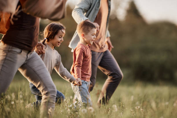 carefree kids running with their parents in the park. - kids stock pictures, royalty-free photos & images