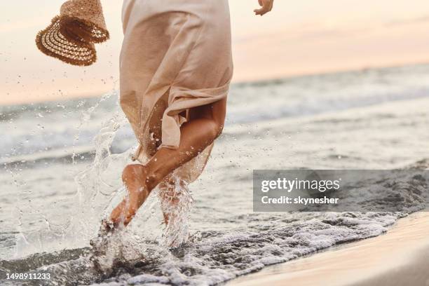 back view of playful woman running through sea on the beach. - droplet sea summer stockfoto's en -beelden