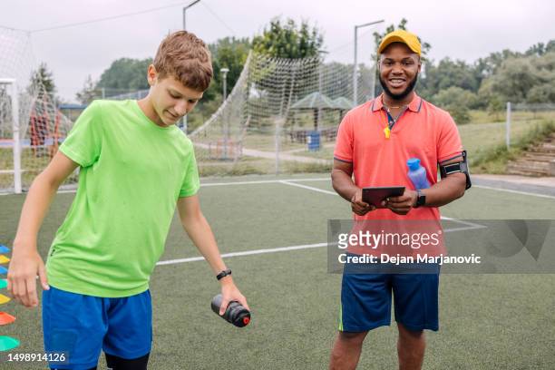 boy having individual soccer training by the black coach using digital tablet - sports training camp 個照片及圖片檔