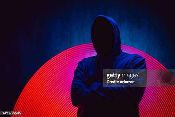 scary faceless man in a hoodie under neon lights - man and his hoodie stockfoto's en -beelden