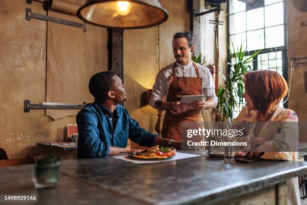 hispanic waiter taking order from multiracial couple. - setting the bar stock pictures, royalty-free photos & images